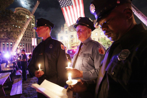 Firefighters hold candles during the vigil to remember fallen firefighters.