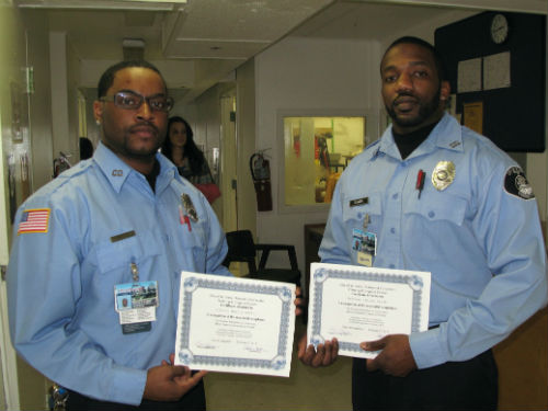 Officers Marcus Cotton and Damion Smith holding Instructor Certificates