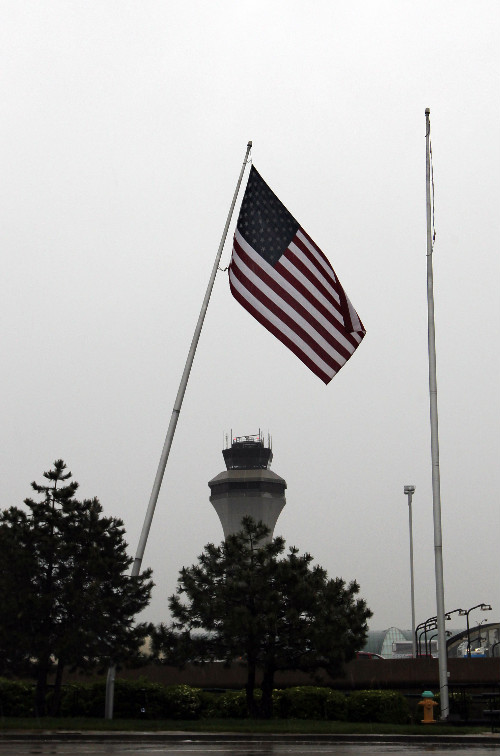 American Flag on tilted flagpole waves over Lambert Airport Tower. Damaged by the tornado, but still standing.